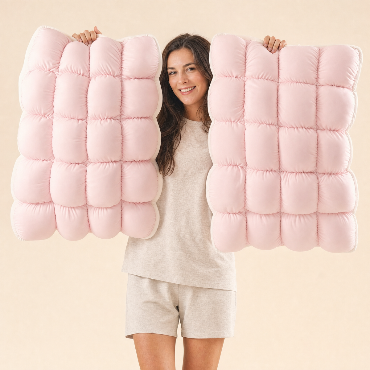 Woman holding up two Baby Pink Lune pillows