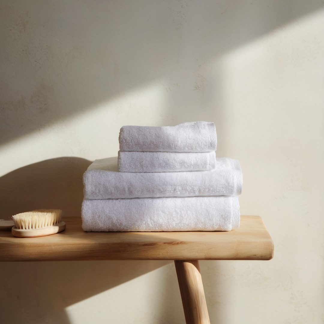 Folded Truenova cotton towels stacked on a wooden bench
